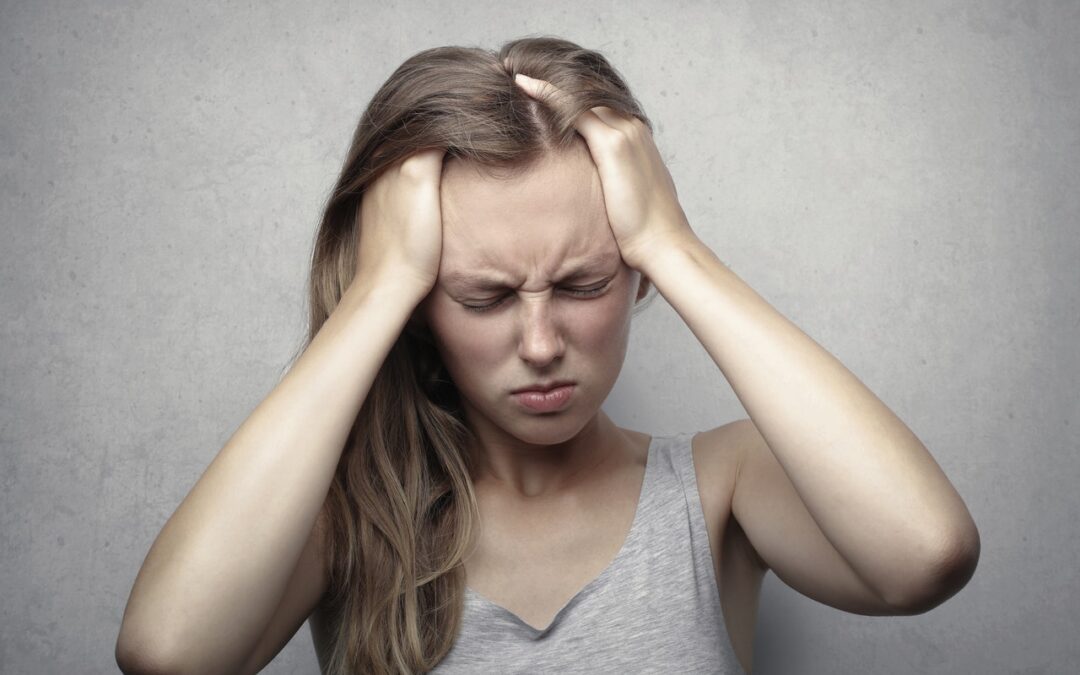 Woman holding hands to her head and looking stressed